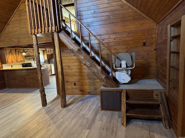 stairway featuring lofted ceiling, wood-type flooring, wooden ceiling, and wooden walls