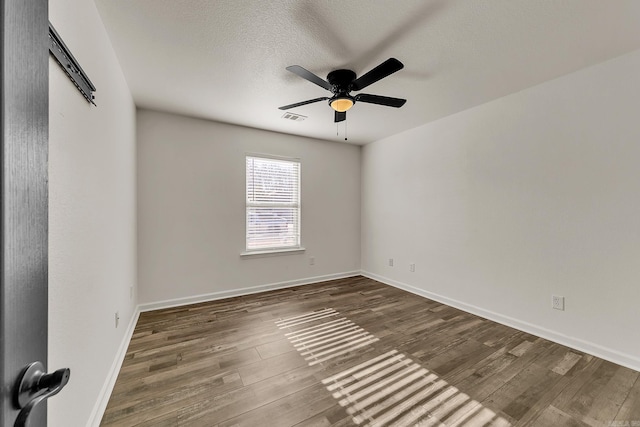 spare room with a textured ceiling, dark hardwood / wood-style flooring, and ceiling fan