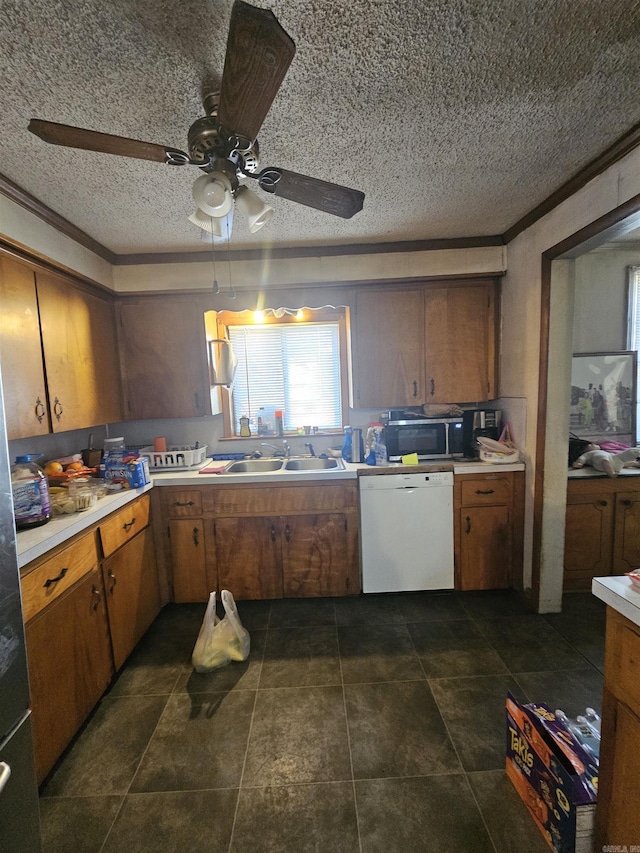 kitchen with dishwasher, sink, ceiling fan, dark tile patterned floors, and a textured ceiling