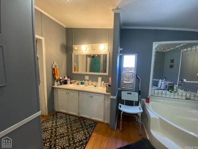 bathroom with wood-type flooring, a textured ceiling, a bathtub, and crown molding