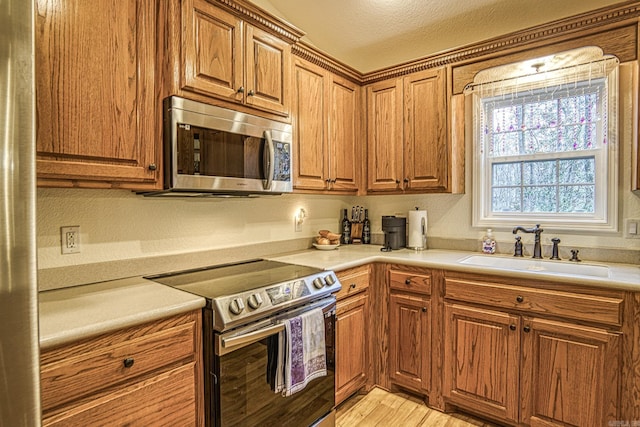 kitchen featuring appliances with stainless steel finishes, light wood-type flooring, a textured ceiling, and sink