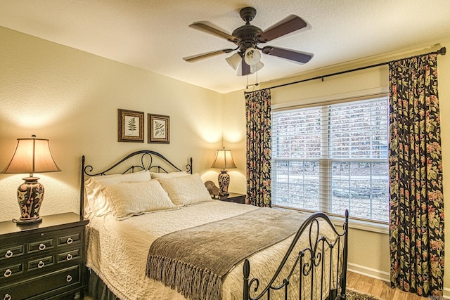 bedroom with ceiling fan, wood-type flooring, a textured ceiling, and multiple windows