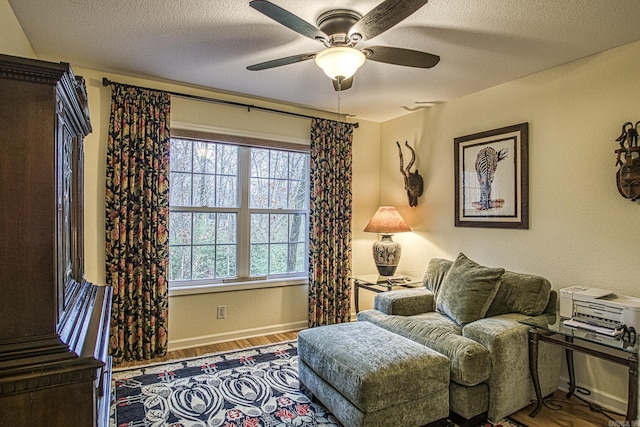 living area featuring a textured ceiling, hardwood / wood-style flooring, and ceiling fan