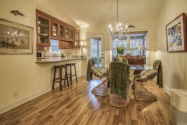 dining space with an inviting chandelier, lofted ceiling, and hardwood / wood-style flooring