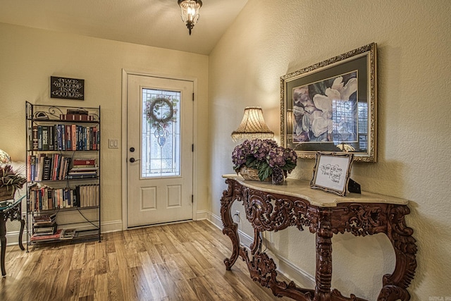 entryway with light hardwood / wood-style floors and vaulted ceiling