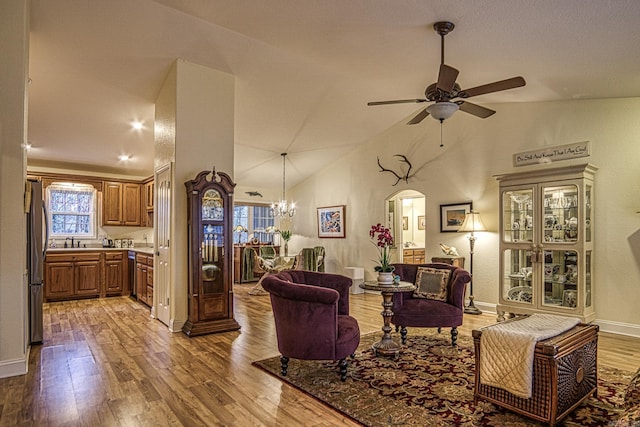 living room featuring hardwood / wood-style floors, high vaulted ceiling, ceiling fan with notable chandelier, and sink