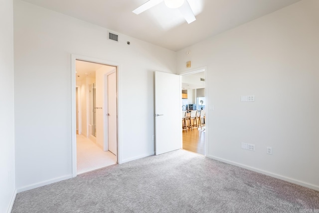 empty room with ceiling fan and light carpet