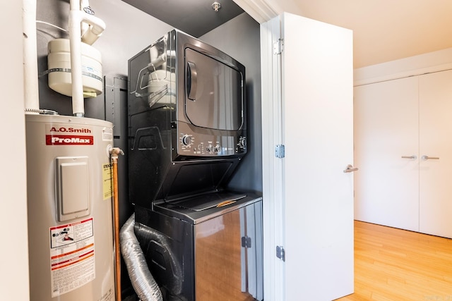 laundry area with wood-type flooring, stacked washer / dryer, and water heater