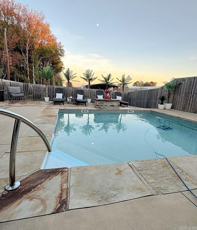 pool at dusk featuring a patio area