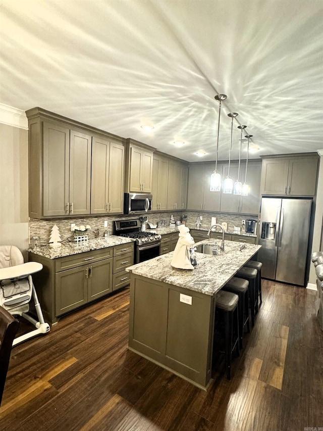 kitchen with pendant lighting, sink, stainless steel appliances, light stone countertops, and a center island with sink