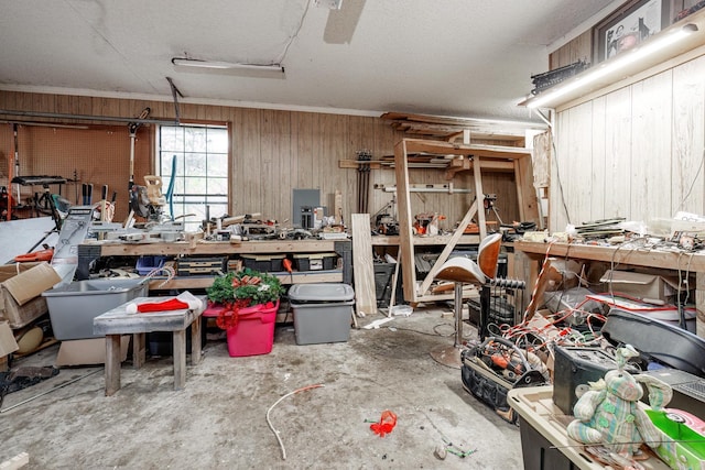 interior space featuring a workshop area, a textured ceiling, wooden walls, and concrete floors