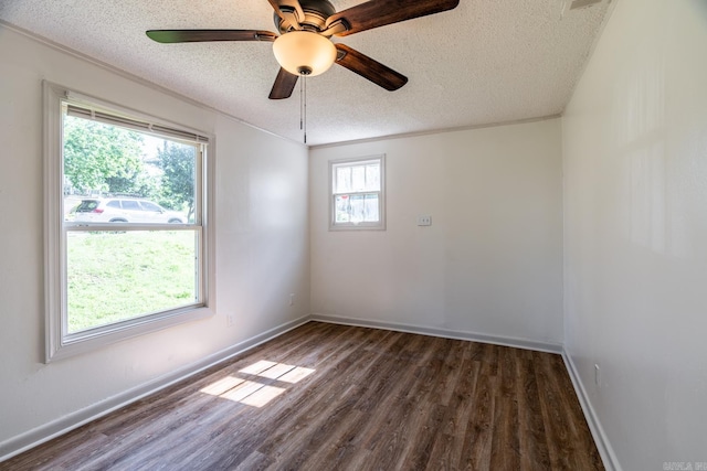 empty room featuring a textured ceiling, dark hardwood / wood-style floors, ceiling fan, and a healthy amount of sunlight