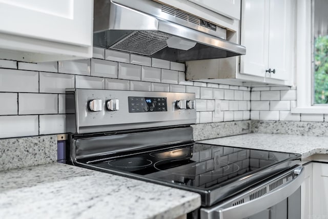 kitchen featuring light stone countertops, white cabinets, stainless steel electric range, and ventilation hood