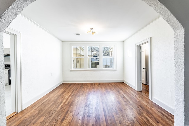 spare room featuring crown molding and dark wood-type flooring