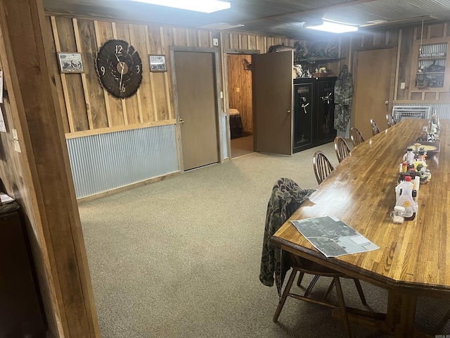 carpeted dining area featuring wood walls