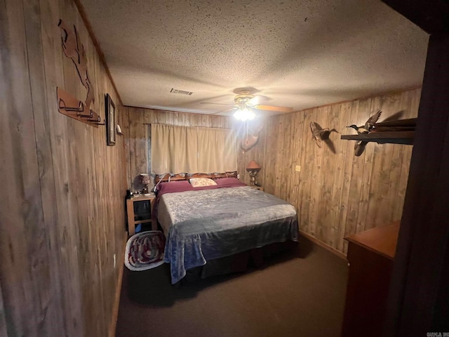 bedroom featuring ceiling fan, wood walls, and a textured ceiling