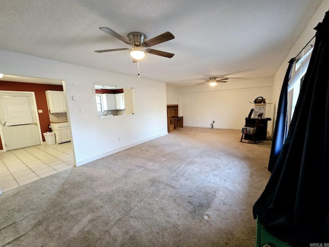 unfurnished living room featuring a wood stove, light carpet, ceiling fan, and a textured ceiling