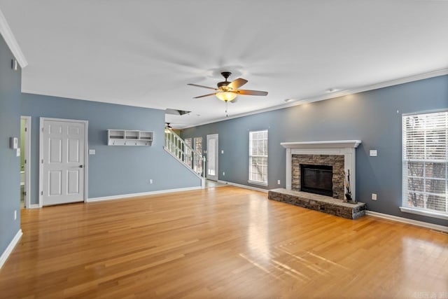 unfurnished living room featuring a stone fireplace, ornamental molding, and hardwood / wood-style flooring