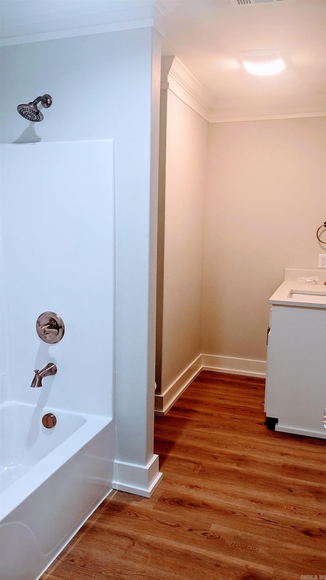 bathroom with hardwood / wood-style flooring, vanity, ornamental molding, and bathtub / shower combination