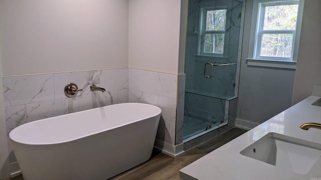 bathroom featuring plus walk in shower, vanity, hardwood / wood-style flooring, and tile walls