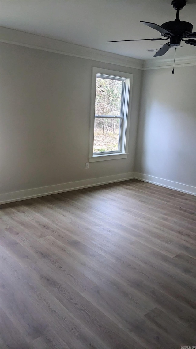 empty room featuring crown molding, ceiling fan, and wood-type flooring