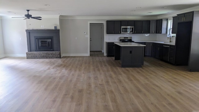 kitchen with hardwood / wood-style floors, ceiling fan, ornamental molding, appliances with stainless steel finishes, and a kitchen island