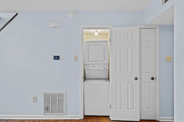 washroom featuring stacked washer / dryer and light hardwood / wood-style flooring