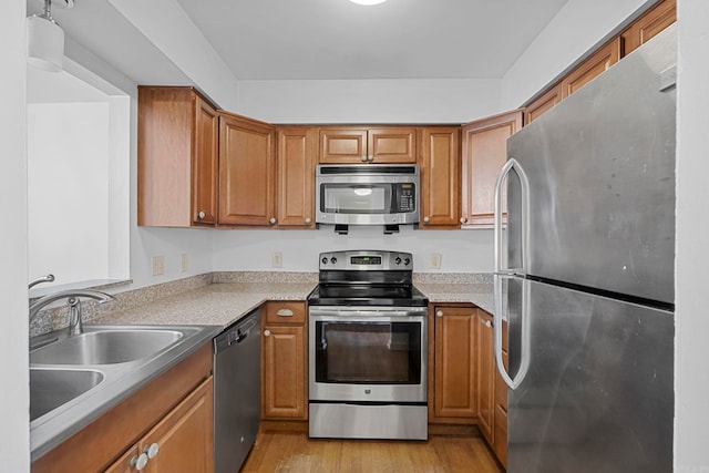 kitchen featuring light wood-type flooring, stainless steel appliances, and sink