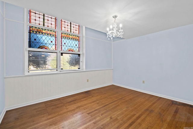 spare room with wood-type flooring and a notable chandelier