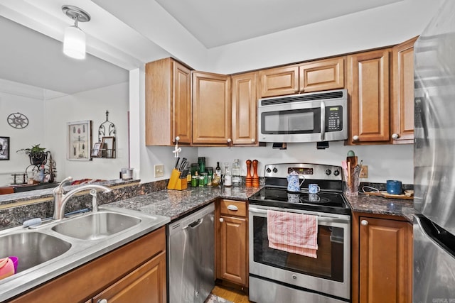 kitchen with pendant lighting, sink, appliances with stainless steel finishes, and dark stone counters