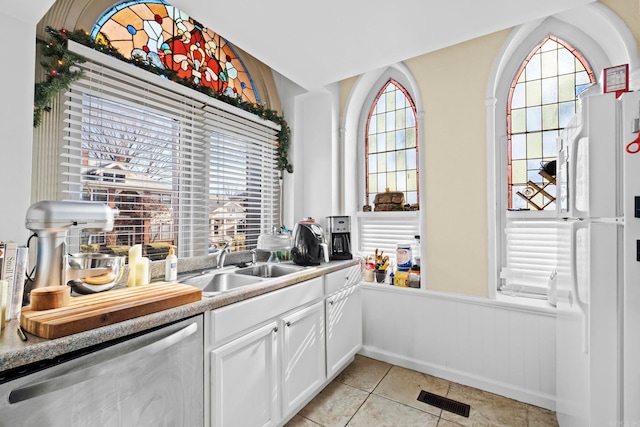 kitchen with dishwasher, white cabinets, and a wealth of natural light