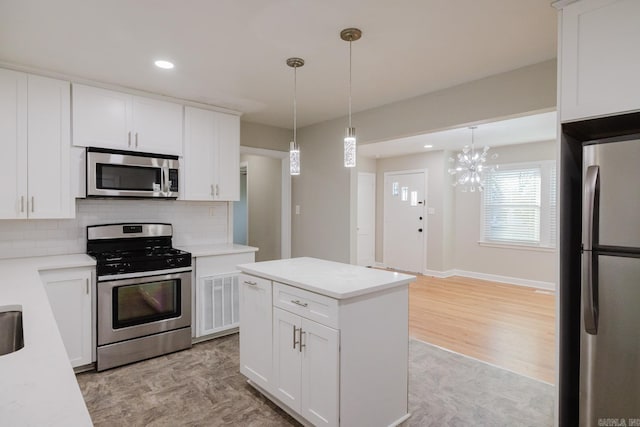 kitchen featuring backsplash, stainless steel appliances, pendant lighting, light hardwood / wood-style flooring, and white cabinetry