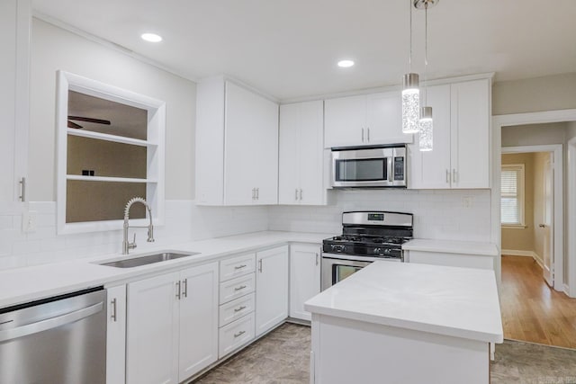 kitchen featuring backsplash, stainless steel appliances, sink, white cabinetry, and hanging light fixtures