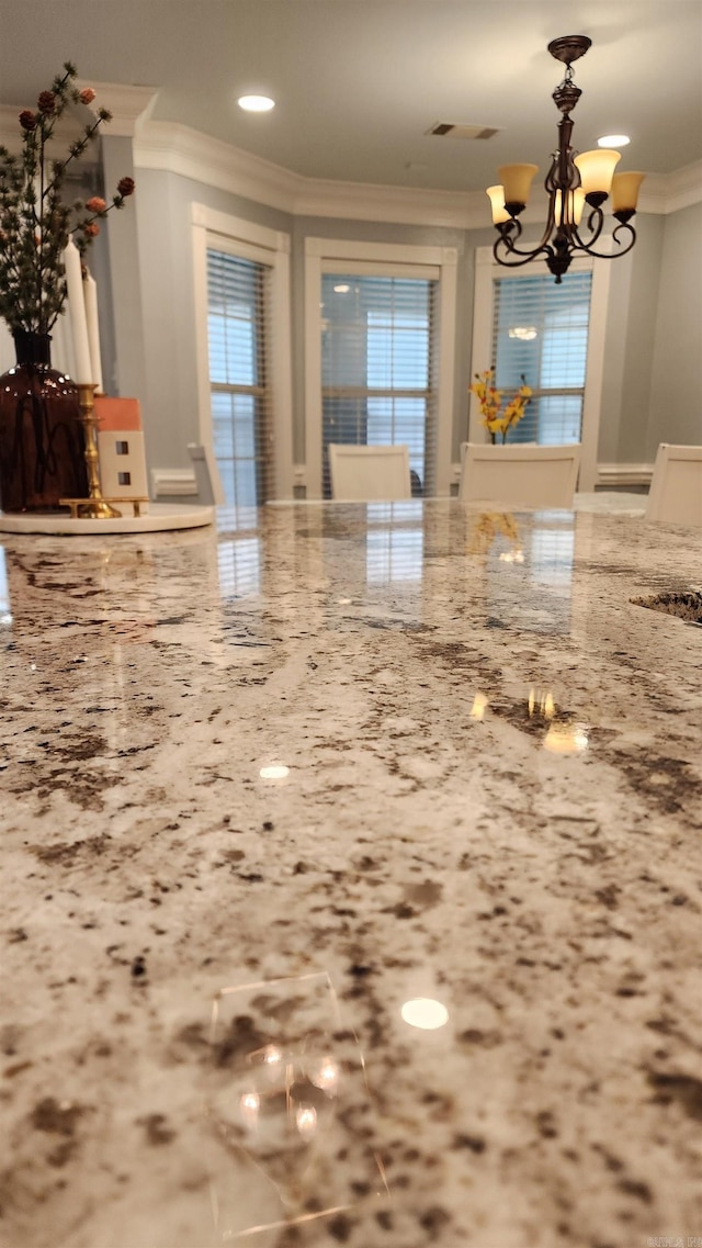 kitchen with light stone counters, an inviting chandelier, hanging light fixtures, and ornamental molding