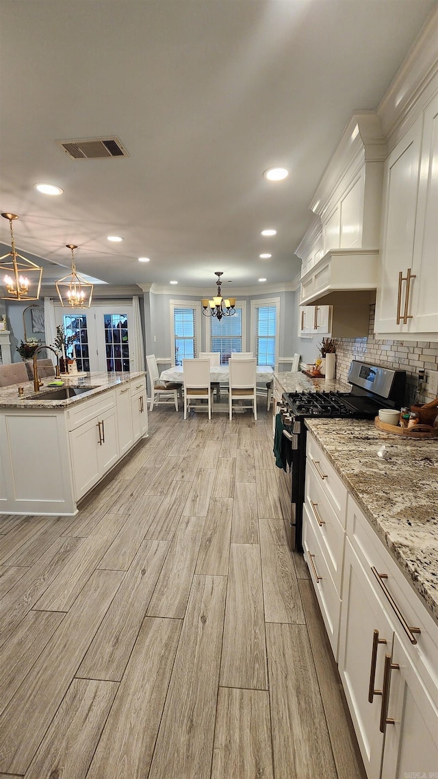 kitchen with white cabinets, pendant lighting, and stainless steel range with gas stovetop