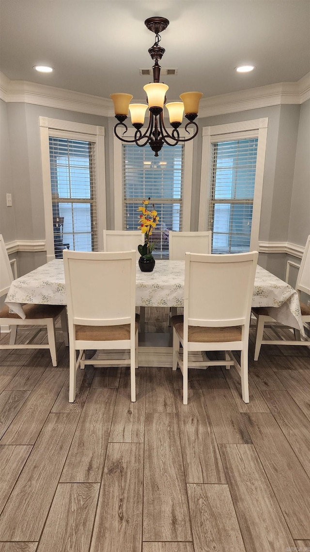 dining room with a chandelier, wood-type flooring, and ornamental molding