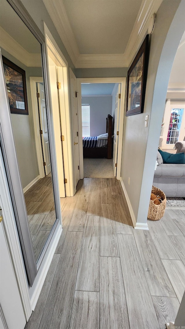 hallway with light hardwood / wood-style floors and ornamental molding