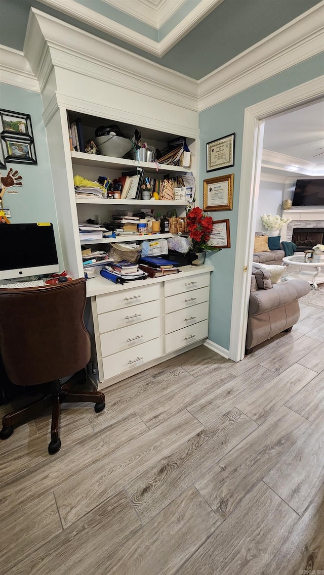 office area featuring built in desk, light wood-type flooring, and ornamental molding