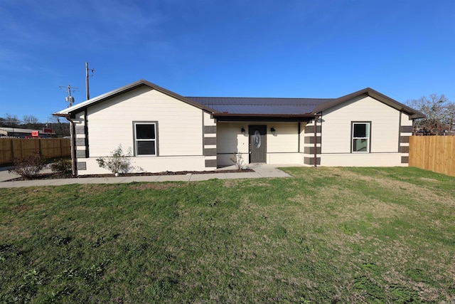 view of front facade featuring solar panels and a front yard