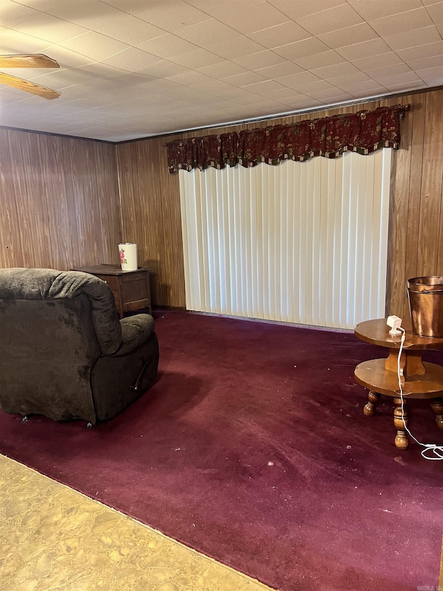 living area with carpet floors and wooden walls