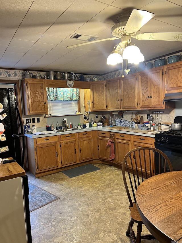 kitchen with black appliances, ceiling fan, premium range hood, and sink