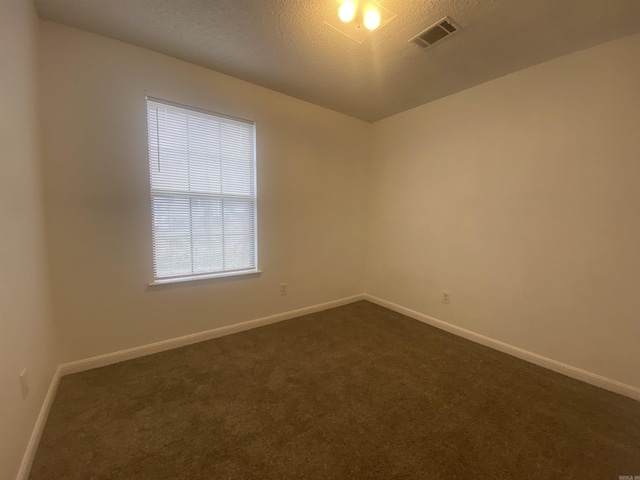 carpeted empty room with a textured ceiling