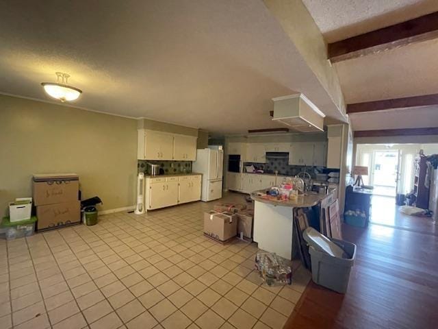 kitchen with white refrigerator, extractor fan, white cabinetry, a textured ceiling, and beamed ceiling