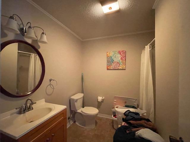 bathroom featuring a textured ceiling, ornamental molding, toilet, and vanity