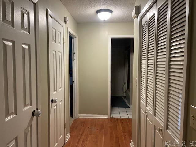 hall featuring light wood-type flooring and a textured ceiling