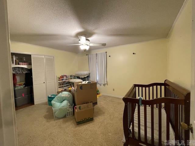 carpeted bedroom with a textured ceiling, ceiling fan, and a nursery area