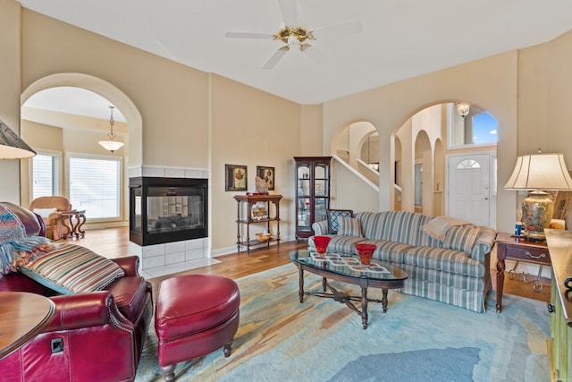 living room with a tile fireplace, ceiling fan, and light hardwood / wood-style flooring