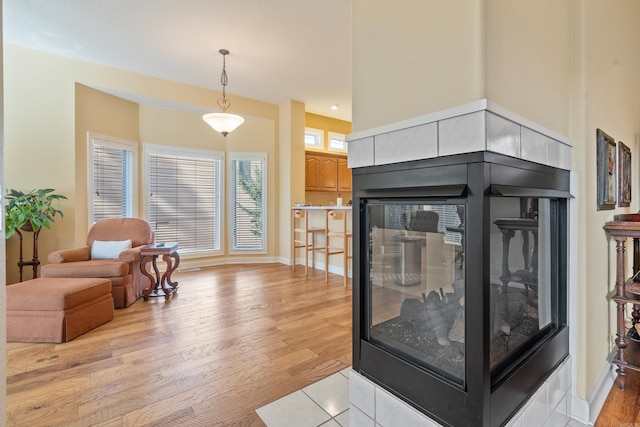 living room featuring light wood-type flooring and a tiled fireplace