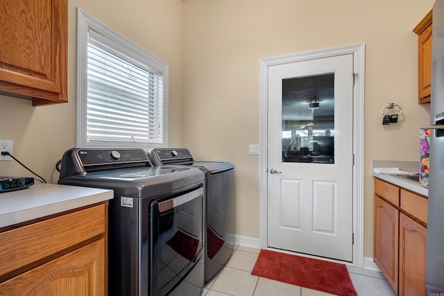 laundry area with cabinets, independent washer and dryer, and light tile patterned floors