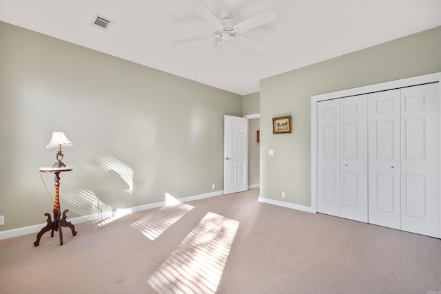 unfurnished bedroom featuring ceiling fan, a closet, and light carpet